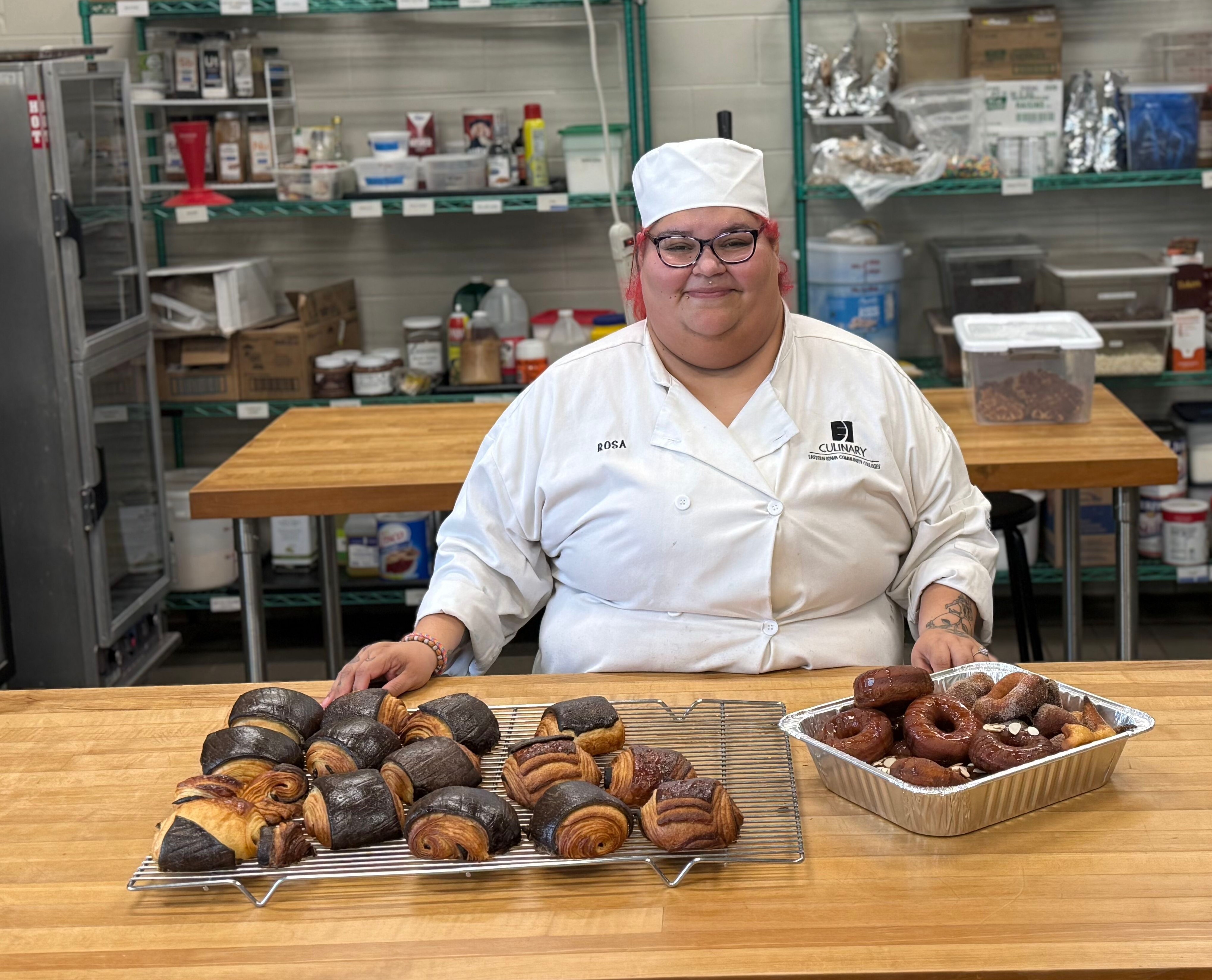 Rosamarie Gomez stands by table filled with baked goods she made in class.